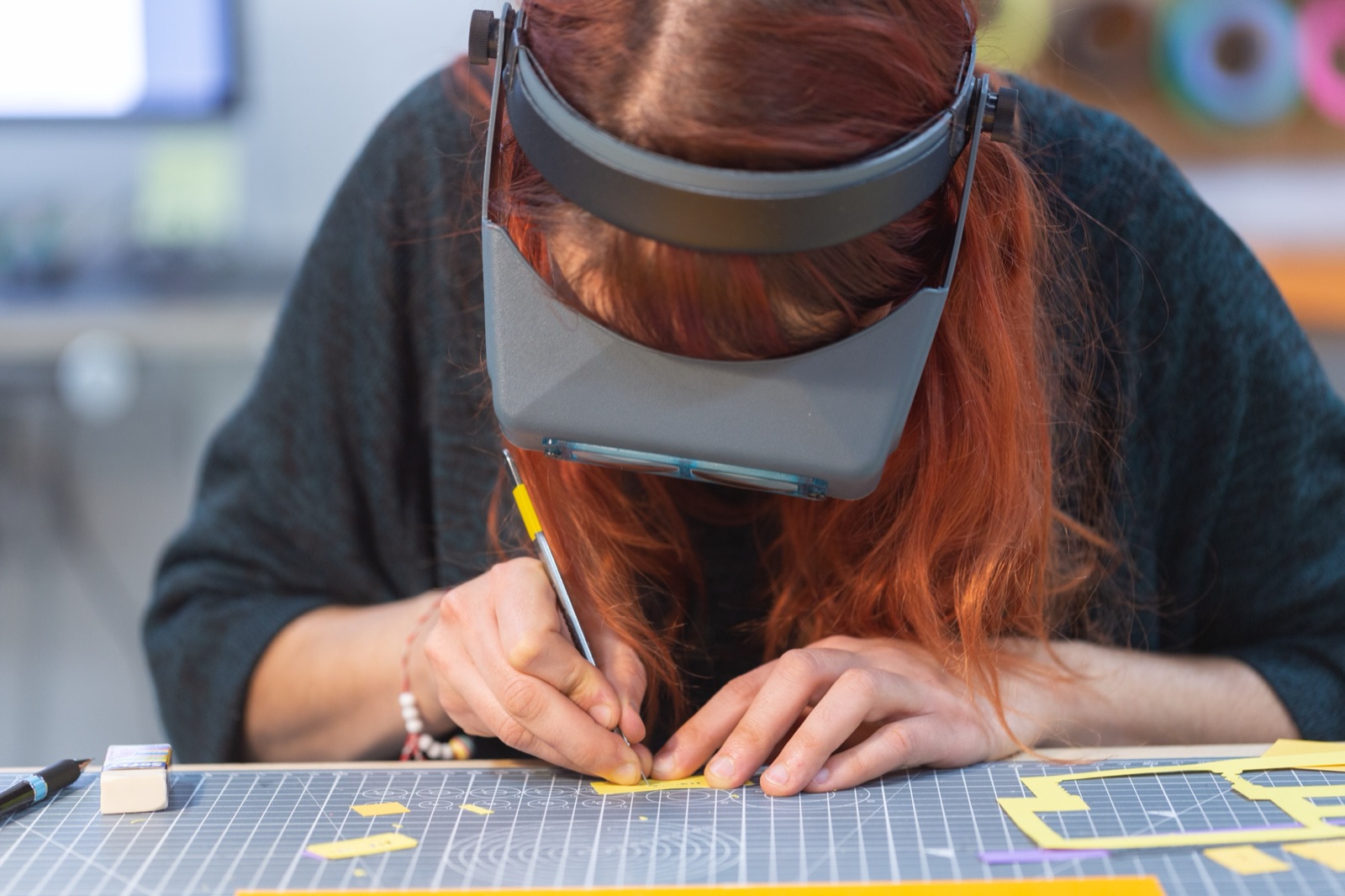 Close-up of a maker cutting paper assets for the animation, wearing a magnifying visor for precision work