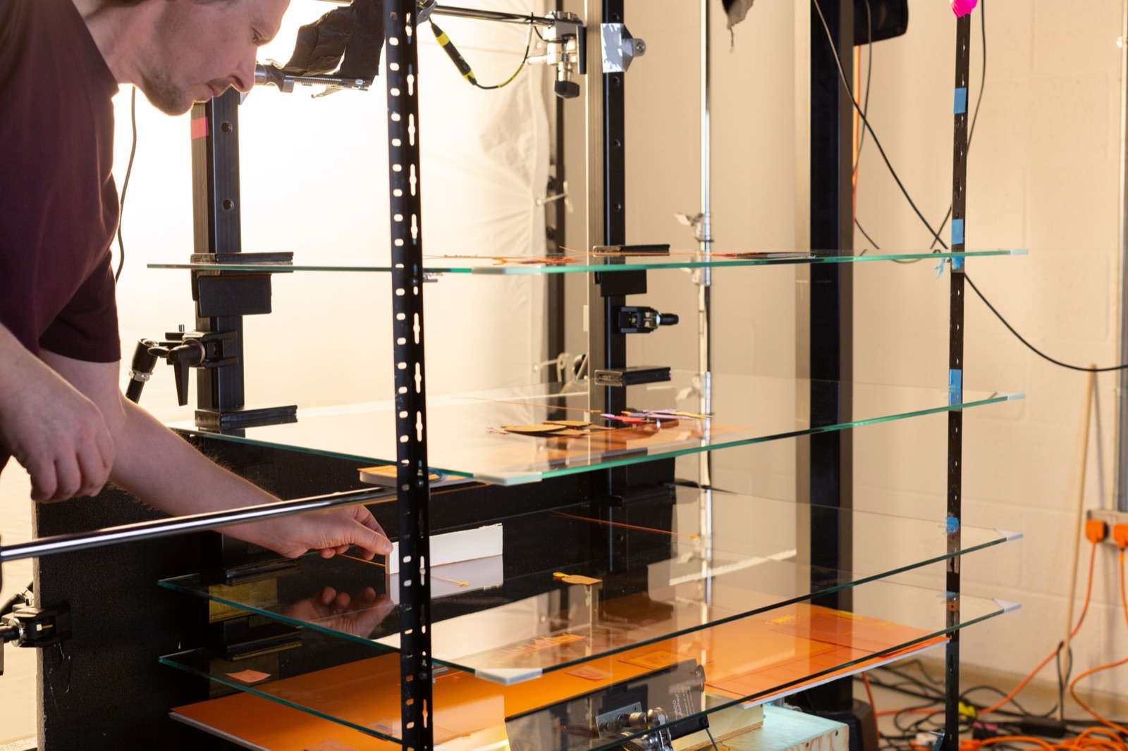 The glass multi-plane rig in the studio — multiple layers of glass on a steel frame, with paper elements placed at different depths