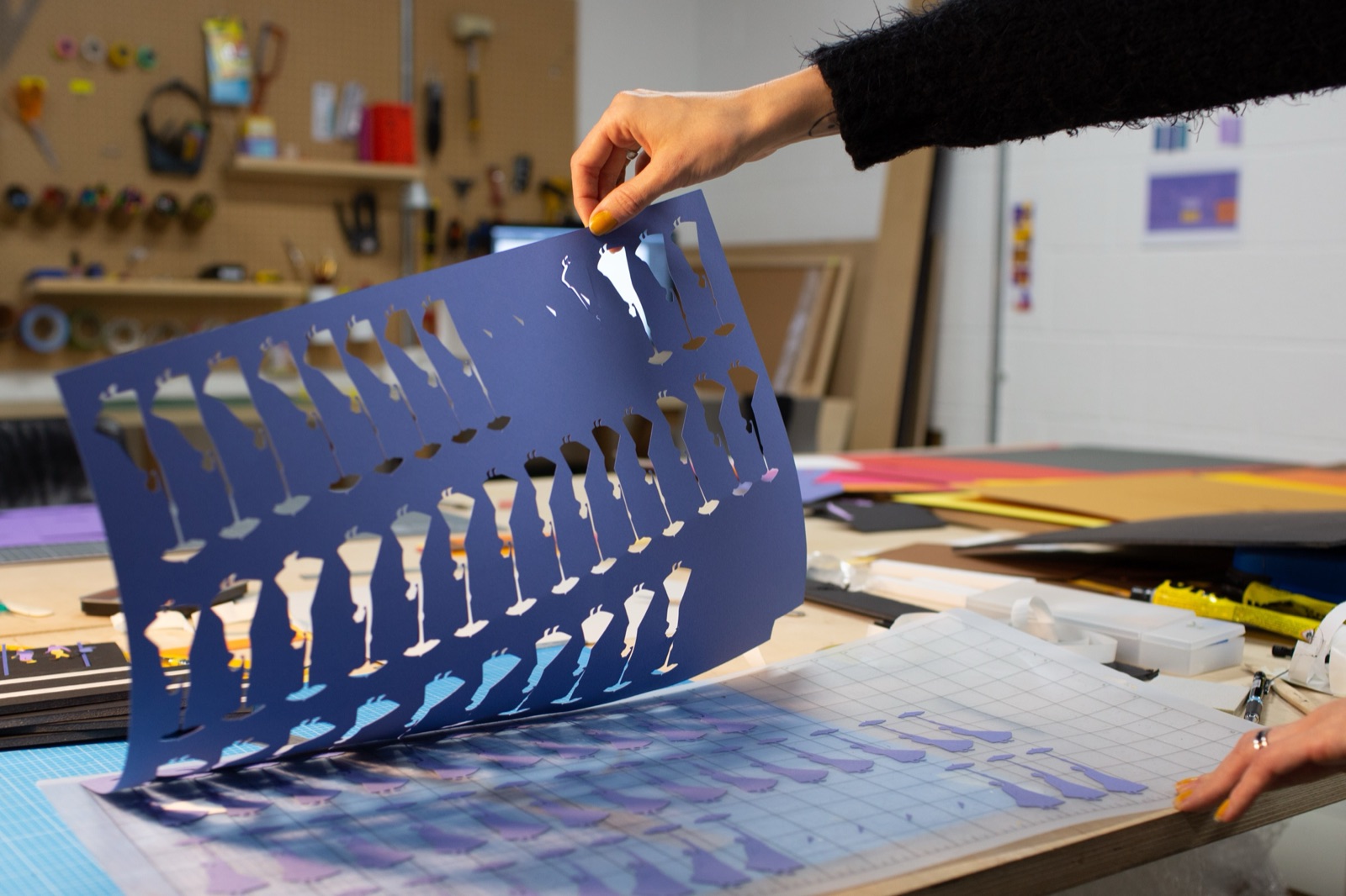Paper cut-outs for the champagne pour sequence — each frame individually cut from card, held up against the cutting mat