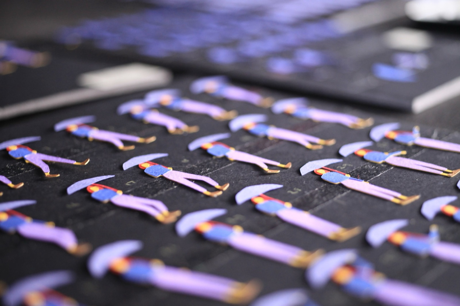 Rows of numbered replacement animation pieces for the umbrella character — each tiny paper figure laid out in sequence on a black surface