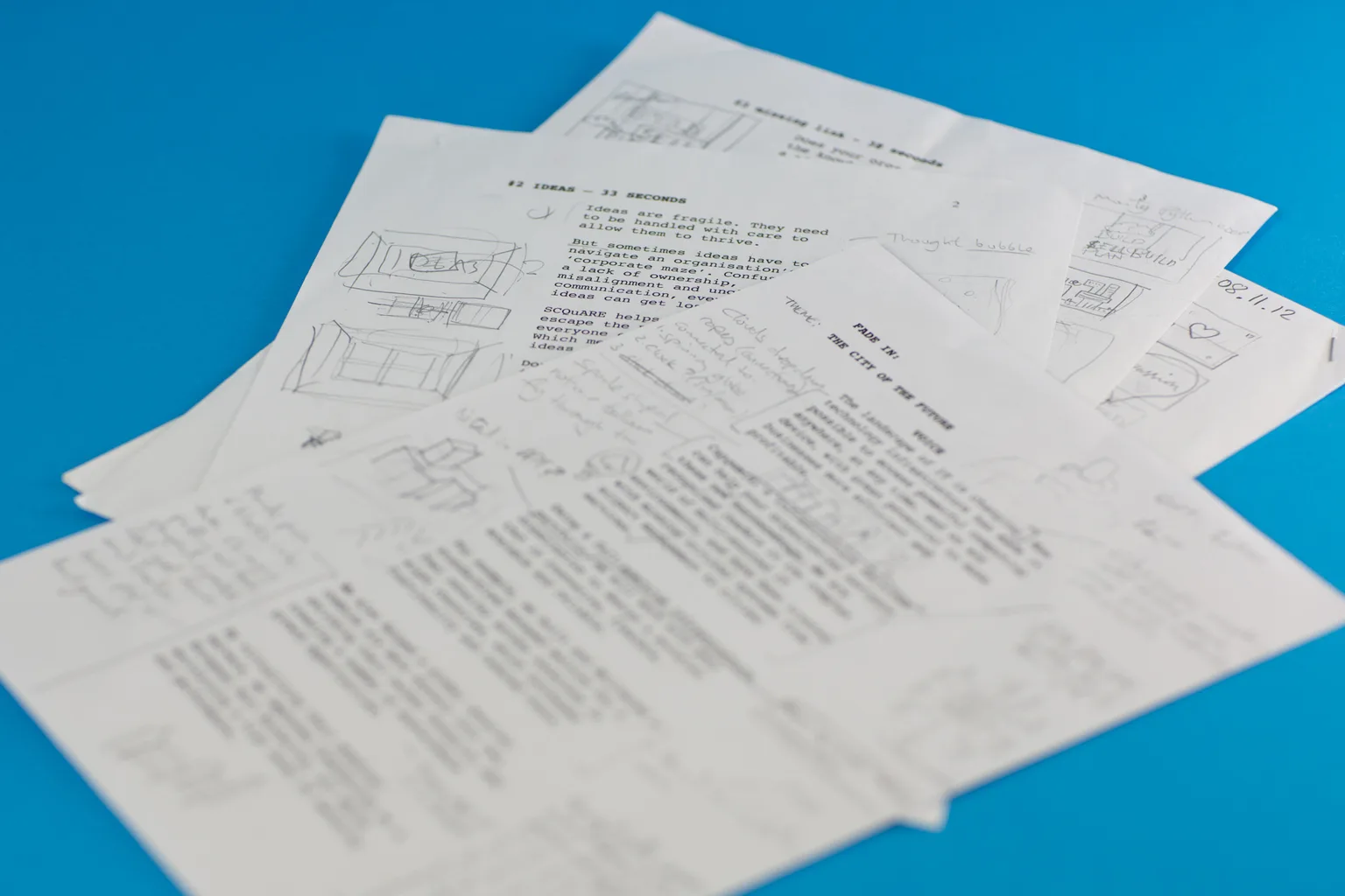 Printed explainer-video script pages covered in handwritten edits and rough thumbnail storyboard sketches — an early working draft